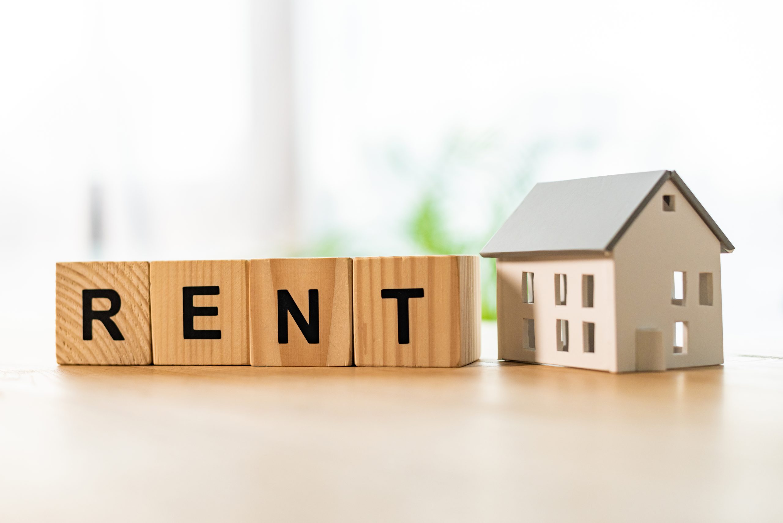 house model near cubes with rent lettering on wooden table rental income